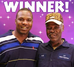 Two men smile together in front of a purple digital background with white stars and white text that reads "Winner!"