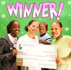 Three women and a young boy smile with an oversized check in front of a green background with white stars and purple text that says "Winner!"