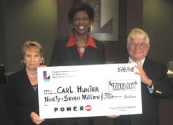 Two women and one man smile together with oversized check in Louisiana Lottery office