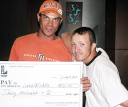 Two men hold a giant check and look at the camera in a Louisiana Lottery office