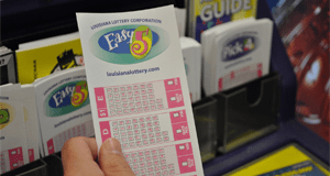 Person selects Easy 5 play slip from a rack of other Lottery game playslips