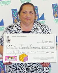 Woman in zebra print shirt holds oversized check in front of a white background patterned with the Louisiana Lottery logo