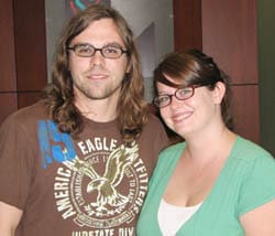 Man and woman with glasses smile together in a Louisiana Lottery office