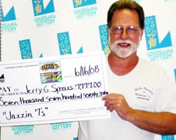 Man with white beard and white tshirt smiles with oversized check in front of a white background patterned with the Louisiana Lottery logo