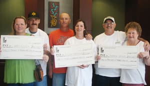 Three couples hold three oversized check and pose for the camera in a Louisiana Lottery office