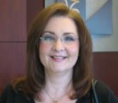 Woman with shoulder length brown hair and glasses smiles in a Louisiana Lottery office