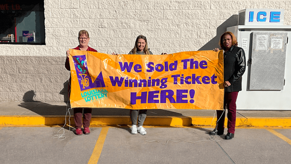 Store Owner Jo Alice Jonesy, Cashier Wendy Guimbllot and Lottery Sales Representative Gladis Major showcase the store’s winner awareness banner after selling the big winning ticket.